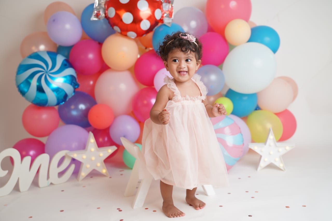 Yanvi in a pink tulle dress taking her first steps among balloons